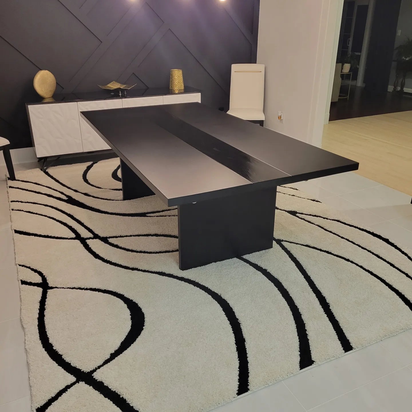 Luxury black plinth-base dining table with matte and gloss two-tone finish in a professional woodworking shop